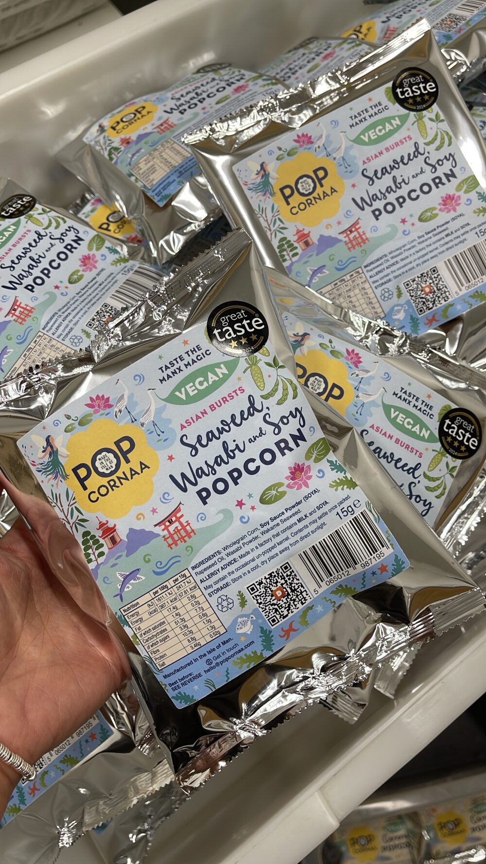 Multiple 15g bags of PopCornaa Vegan Seaweed, Wasabi & Soy Popcorn neatly stacked, ready for packing and distribution. The bags feature vibrant packaging highlighting the bold flavors of seaweed, wasabi, and soy, with clear labels indicating the product’s quality and plant-based nature.